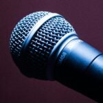 A detailed close-up of a Shure SM58 microphone with an artistic blue lighting effect.