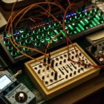 A detailed view of synthesizers and equipment with vibrant lights in a music studio.